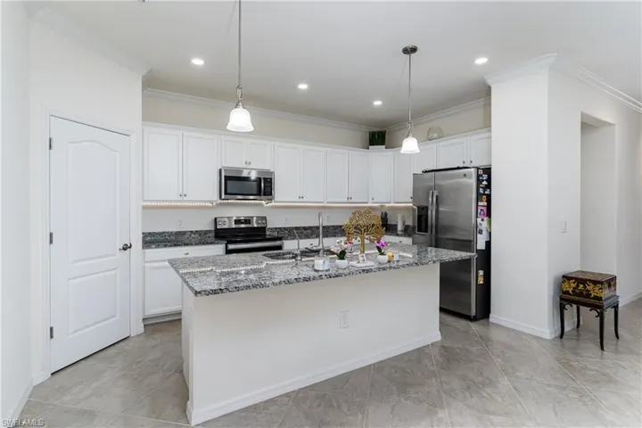 Kitchen featuring stainless steel appliances, a center island with sink, white cabinets, and light tile patterned floors