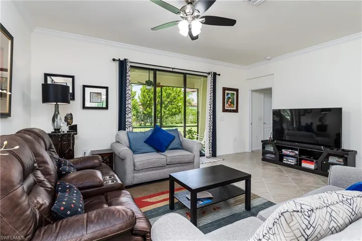 Tiled living room featuring ceiling fan and ornamental molding