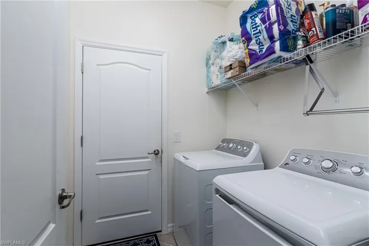 Washroom with separate washer and dryer and tile patterned floors