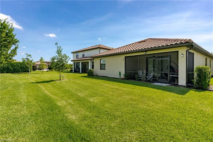 Rear view of house with a sunroom and a lawn