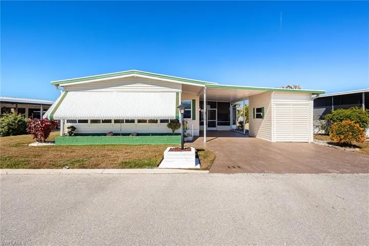 Manufactured / mobile home with a carport, a front yard, and concrete driveway