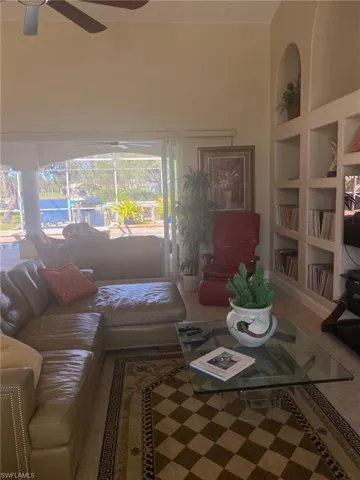 Living room featuring built in shelves and ceiling fan