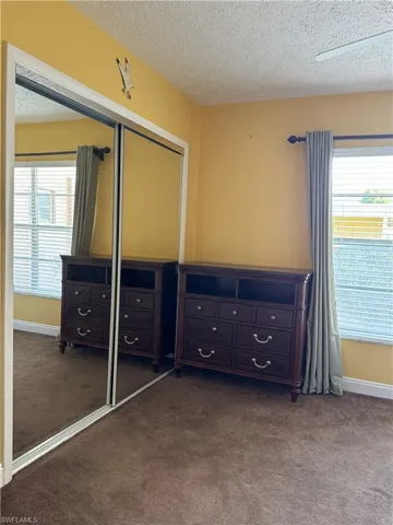Bedroom with a textured ceiling, carpet flooring, and ceiling fan