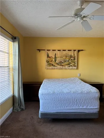 Unfurnished bedroom featuring a textured ceiling, dark colored carpet, and a closet