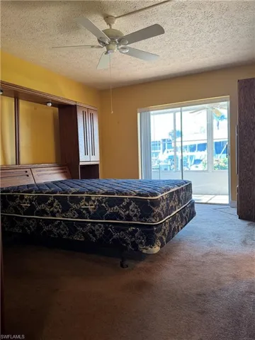 Bedroom with carpet, a textured ceiling, and a ceiling fan