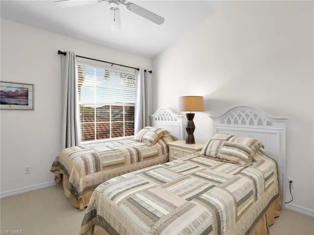 Carpeted bedroom with ceiling fan and lofted ceiling