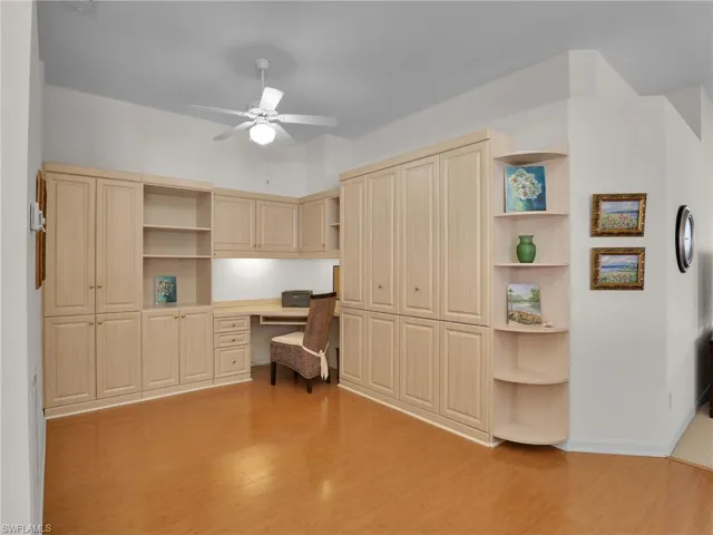 Home office with ceiling fan, built in desk, and light hardwood / wood-style flooring
