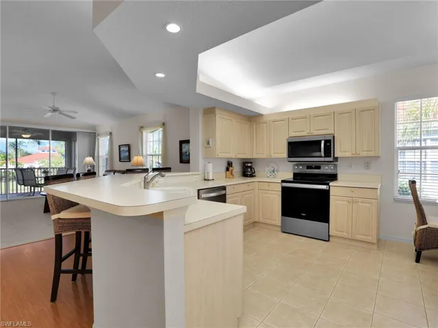 Kitchen with appliances with stainless steel finishes, a wealth of natural light, sink, a kitchen bar, and kitchen peninsula