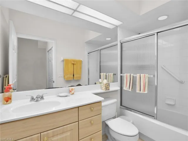 Full bathroom featuring enclosed tub / shower combo, vanity, and toilet