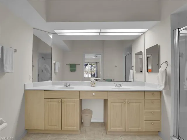 Bathroom with vanity, tile patterned floors, and a shower with door