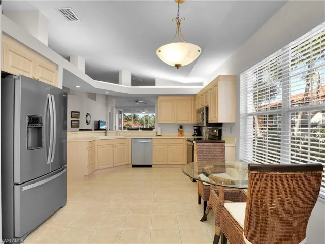 Kitchen with sink, hanging light fixtures, light tile patterned floors, stainless steel appliances, and light brown cabinets
