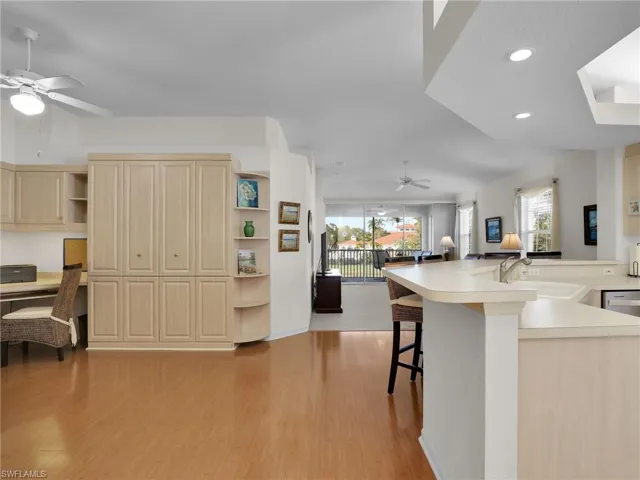 Kitchen with sink, ceiling fan, a kitchen breakfast bar, built in desk, and light wood-type flooring