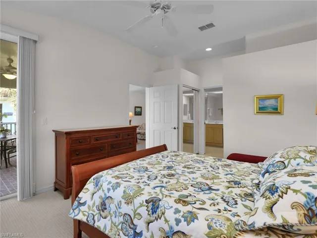 Bedroom featuring ceiling fan, light colored carpet, ensuite bath, and access to outside