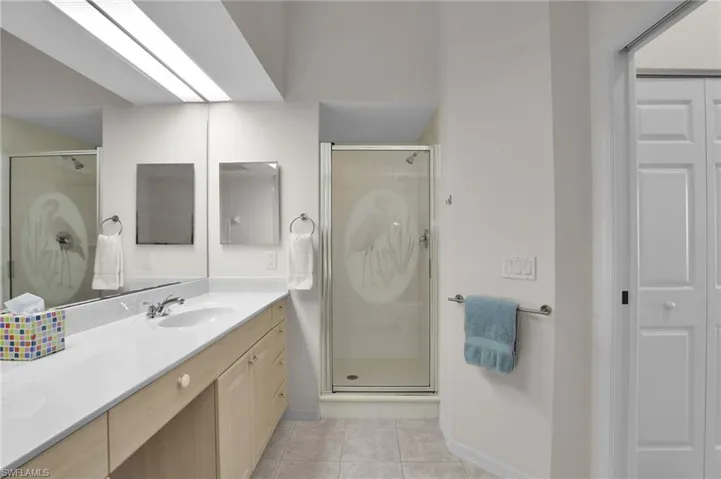 Bathroom featuring tile patterned floors, vanity, and a shower with shower door