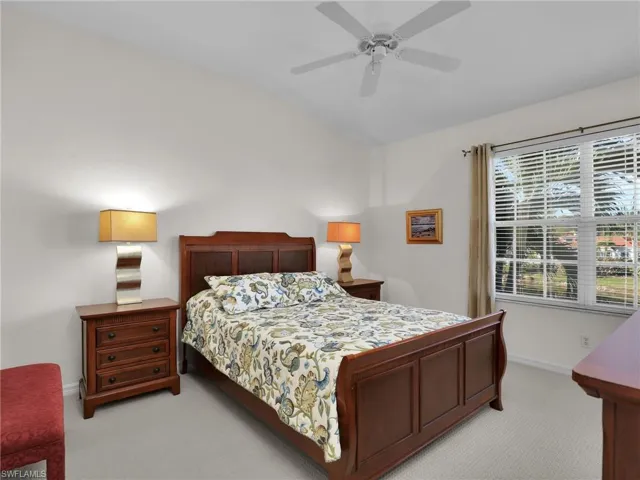 Bedroom featuring ceiling fan, vaulted ceiling, and light carpet