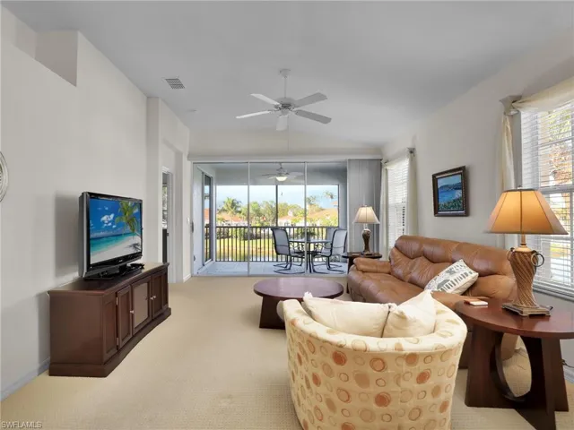 Living room featuring ceiling fan, light colored carpet, plenty of natural light, and vaulted ceiling