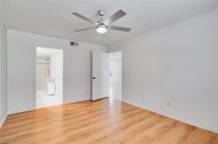 Unfurnished bedroom featuring light wood-style flooring, a ceiling fan, and ensuite bathroom