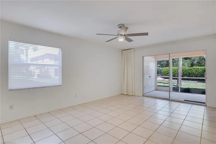 Empty room with a ceiling fan and light tile patterned flooring