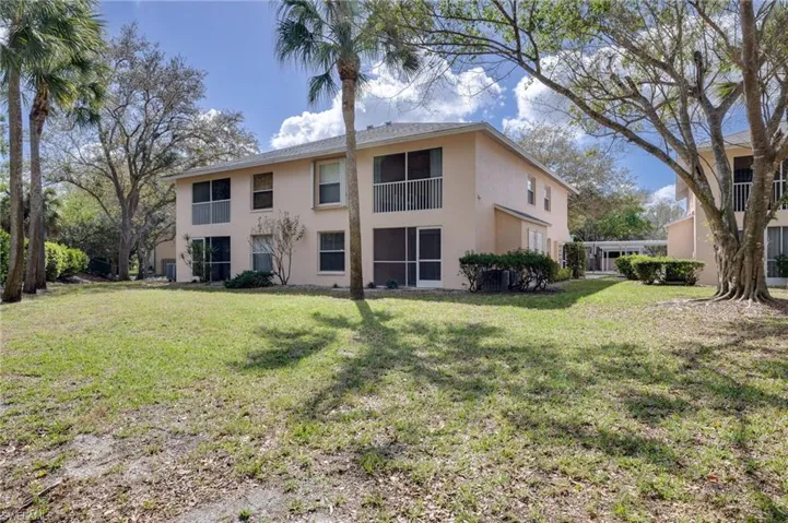 Back of house with stucco siding, a yard, a balcony, and a sunroom