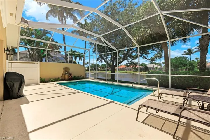 Screened-in patio featuring a swimming pool, concrete decking, and a decorative wall fountain