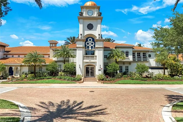 Stately Mediterranean-inspired building featuring a prominent clock tower with a dome, terracotta roof tiles, and manicured landscaping