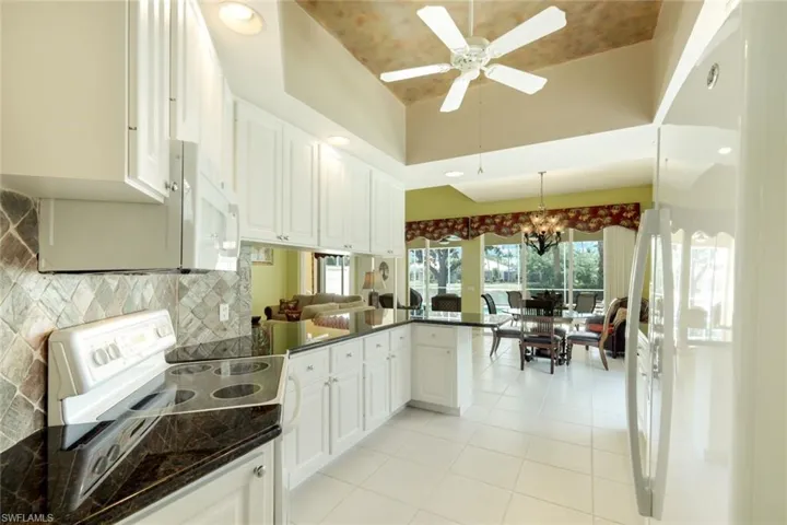 Kitchen featuring white cabinetry, dark stone countertops, and a tiled backsplash
