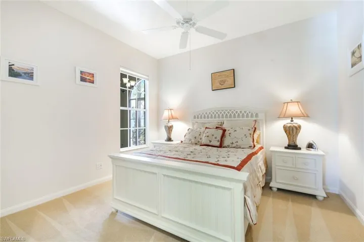 Bedroom featuring a ceiling fan, a window with grid panes, and neutral-toned wall-to-wall carpeting