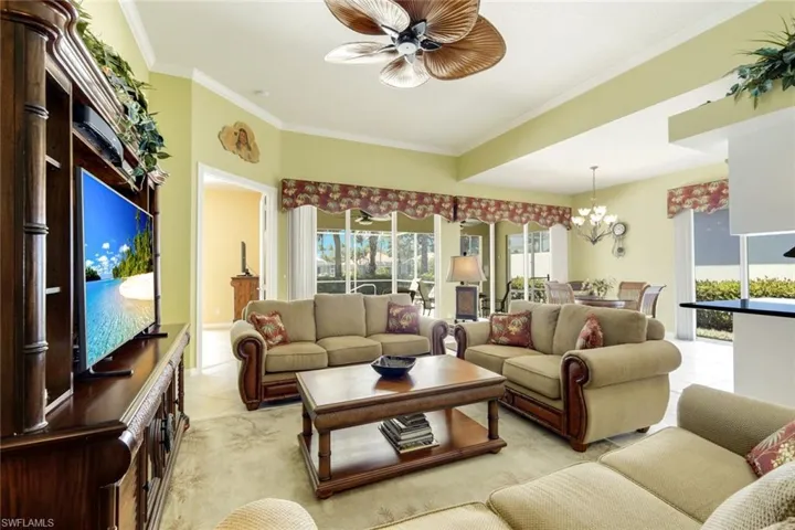 Spacious living area featuring a decorative ceiling fan, crown molding, and large sliding glass doors