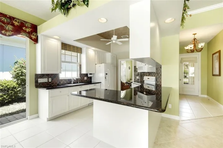 Kitchen with white cabinetry, dark countertops, built-in appliances, recessed lighting, and tile flooring