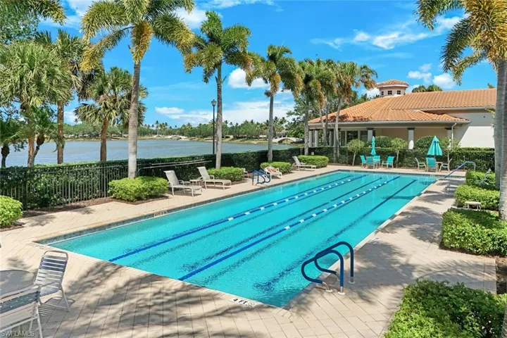 Resort-style pool with lane markers, paver deck, and surrounding lush landscaping