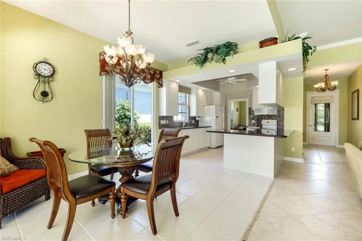 Dining area featuring a glass-top table, a decorative chandelier, and light tile flooring
