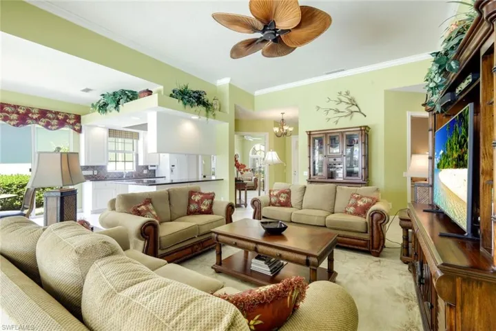 Spacious living area featuring high ceilings, a ceiling fan with tropical-inspired blades, and recessed lighting