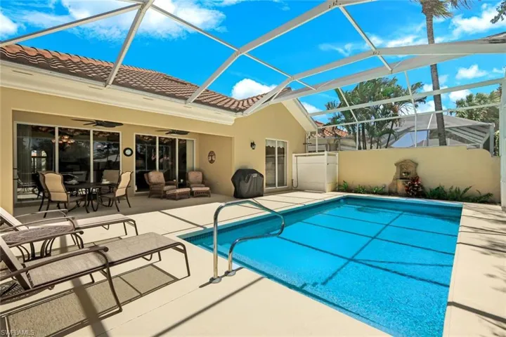Screened-in pool area featuring a blue tiled swimming pool, surrounding patio, and exterior access to the home through multiple sliding glass doors