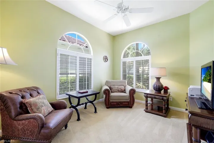 Interior space featuring arched windows with white plantation shutters, vaulted ceilings, and light-colored carpet flooring
