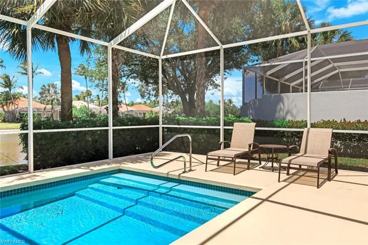 Screened-in pool area featuring a rectangular pool with integrated steps, blue tile accents, and a light-toned concrete deck
