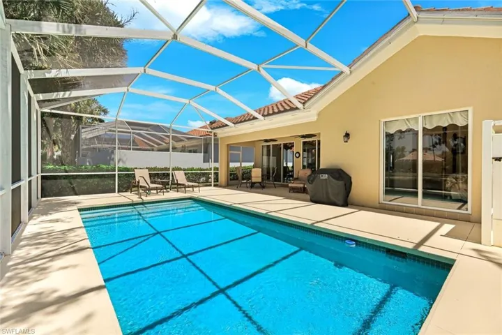 Expansive screened lanai featuring a rectangular swimming pool, spacious concrete decking, and direct access to the interior via sliding glass doors