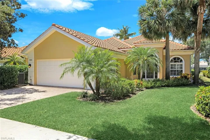 Mediterranean-style exterior featuring a terracotta tile roof, a two-car garage, and a paver driveway