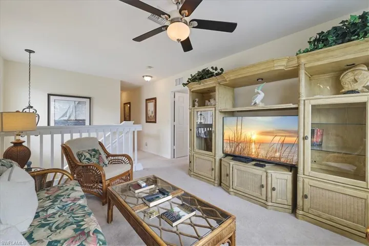 Living area with light colored carpet and a ceiling fan