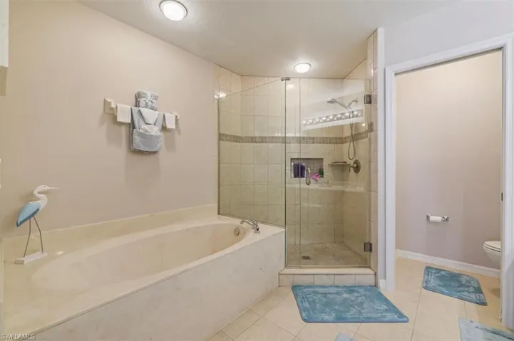 Bathroom with a shower stall, double vanity, and light tile patterned floors