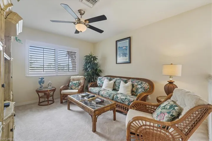 Carpeted bedroom featuring ceiling fan and vaulted ceiling