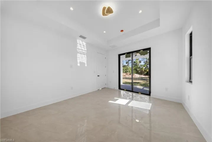 Empty room featuring a tray ceiling and recessed lighting