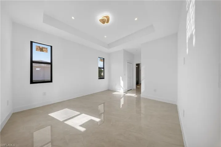 Unfurnished living room with hanging lights and a tray ceiling