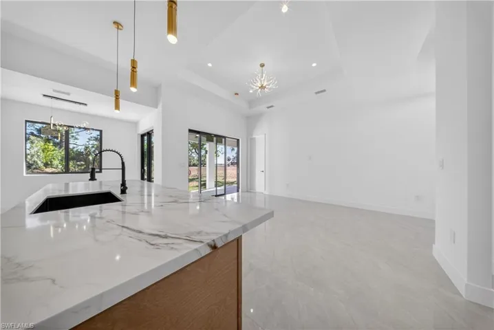 Kitchen featuring white cabinetry, stainless steel appliances, glass fronted cabinets, light stone countertops, and tasteful backsplash