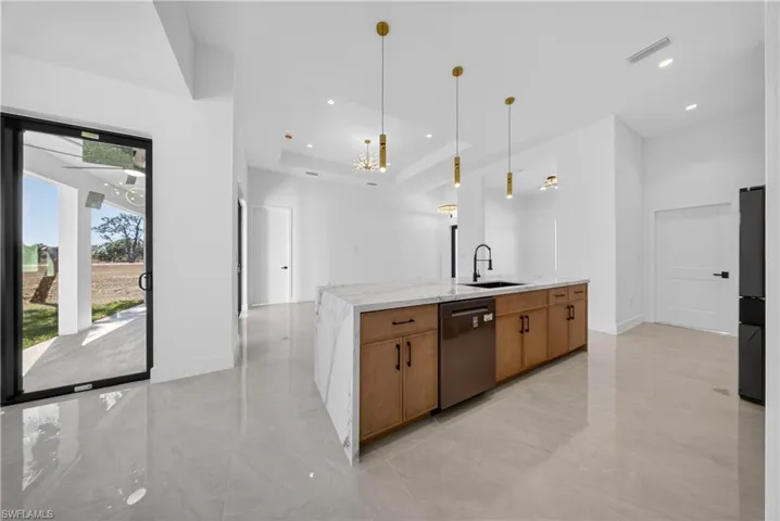 Kitchen featuring dual tone cabinetry, stainless steel appliances, light stone countertops, pendant lighting, and decorative backsplash