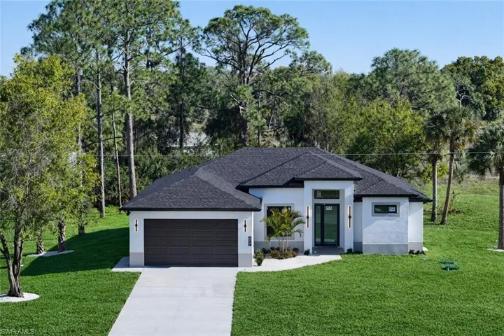 Prairie-style house with a front yard, stucco siding, driveway, and an attached garage