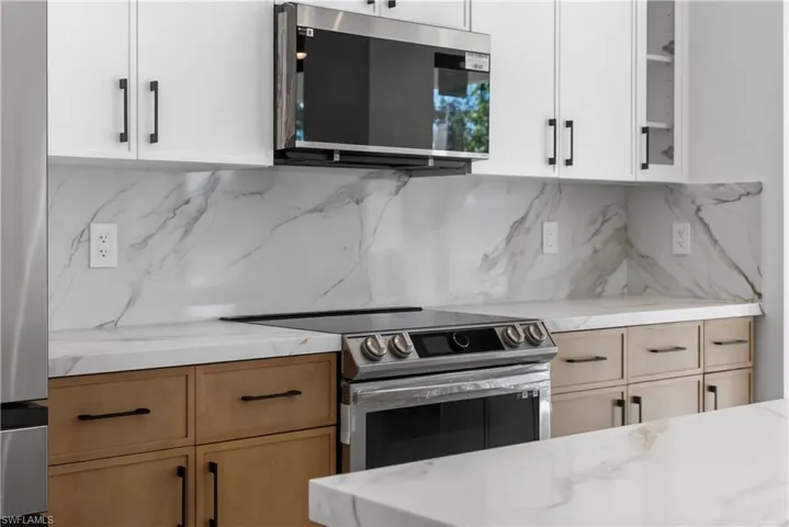 Kitchen featuring light stone countertops and freestanding refrigerator