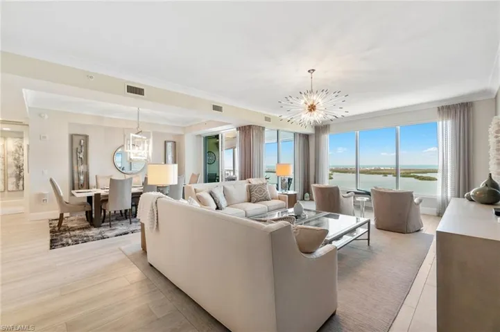 Living area featuring a chandelier, ornamental molding, a water view, light wood finished floors, and baseboards
