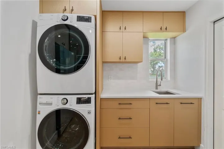 Laundry room featuring stacked washer / dryer and cabinet space
