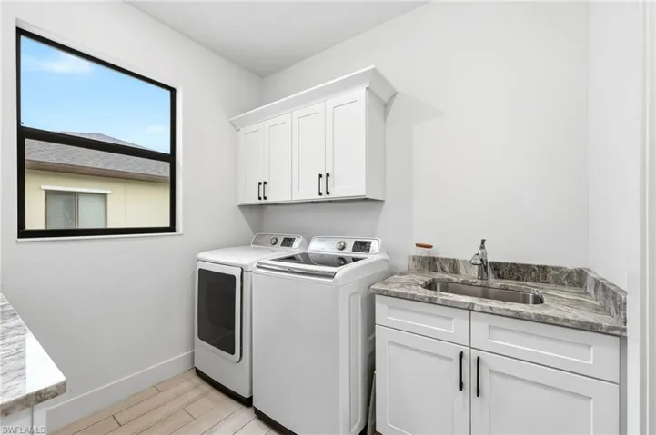 Laundry room with cabinet space, washer and dryer, and light wood finished floors