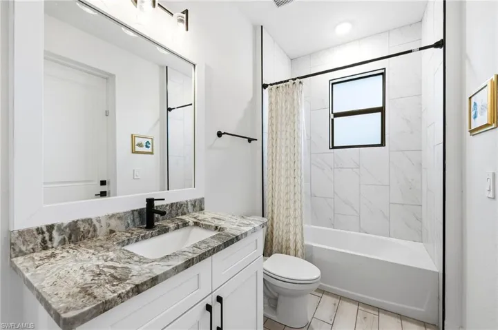 Full bath featuring shower / bath combo with shower curtain, vanity, and wood tiled floors